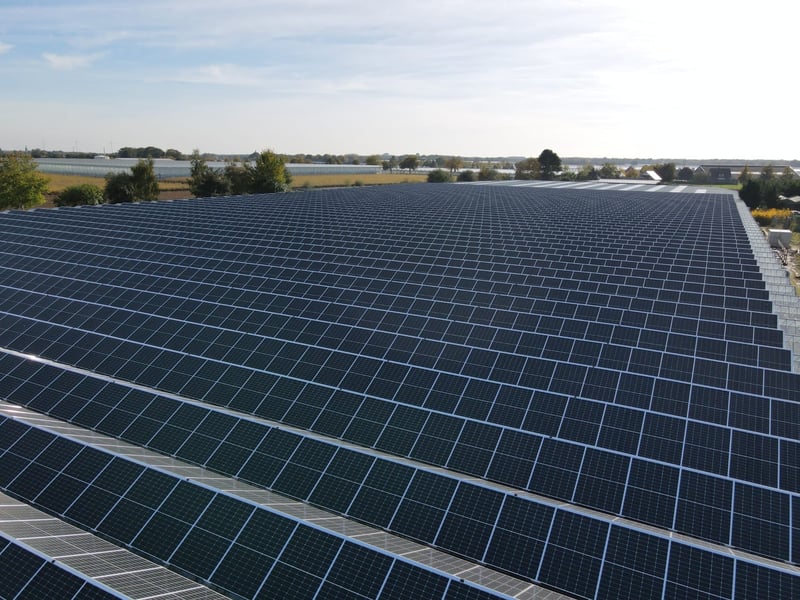 Zonnepanelen op het dak van een bedrijfspand bij zonsondergang